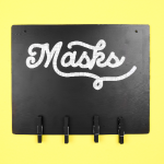 Black mask sign with hooks on a yellow background