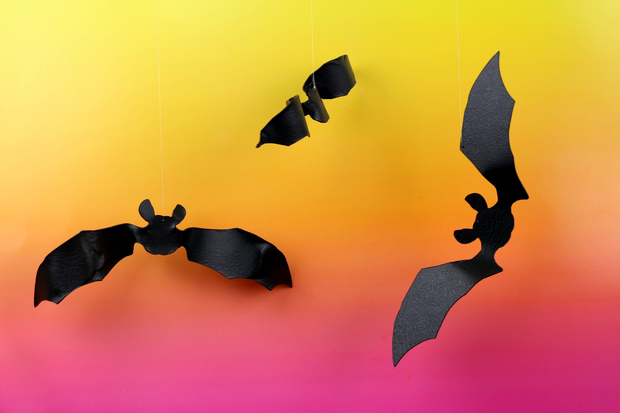 black bat shapes cut out of worbla plastic on pink and orange background