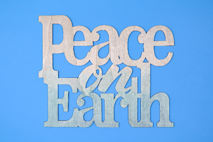 Painted wood Peace on Earth sign on a blue background