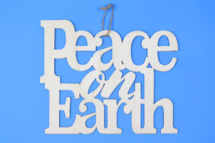 unpainted wood Peace on Earth sign on a blue background