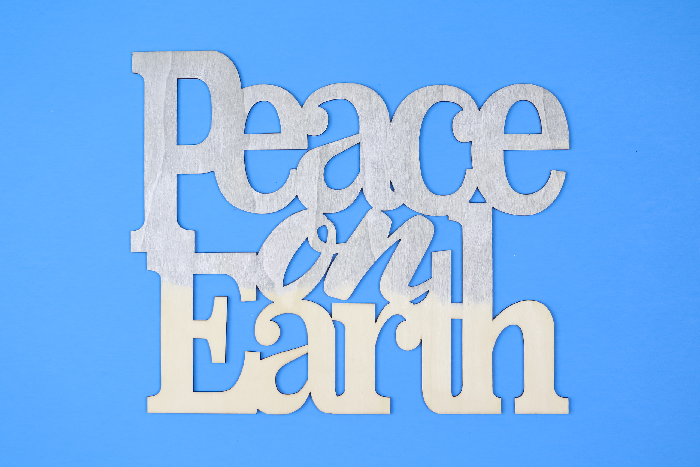 partially painted Peace on Earth sign on a blue background