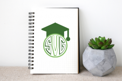 White notebook with green graduation monogram SVG design next to a succulent