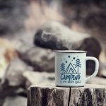 Camping is My Happy Place mug of hot steaming coffee sitting on an old log