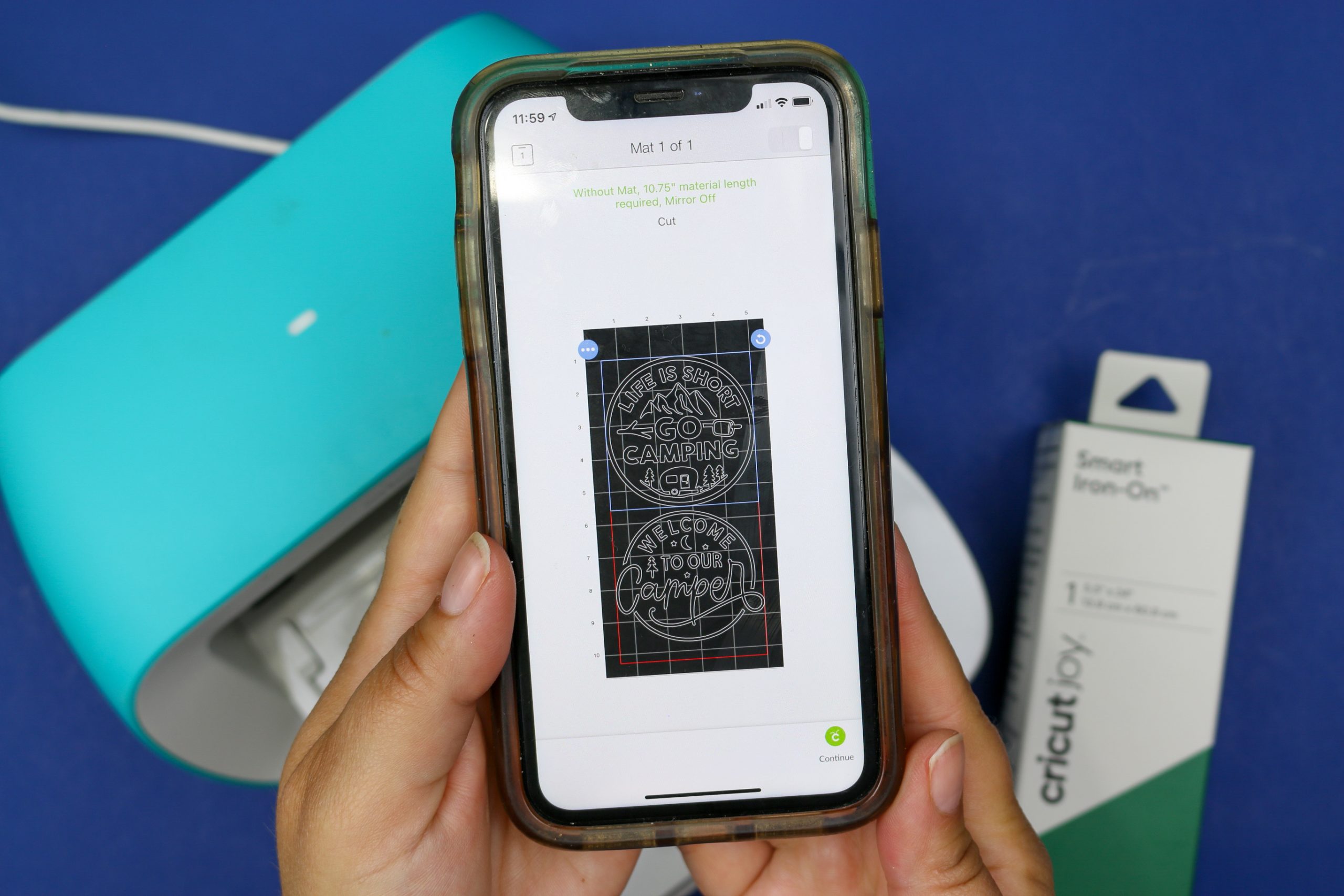 hands holding a smart phone displaying camping designs in Cricut Design Space