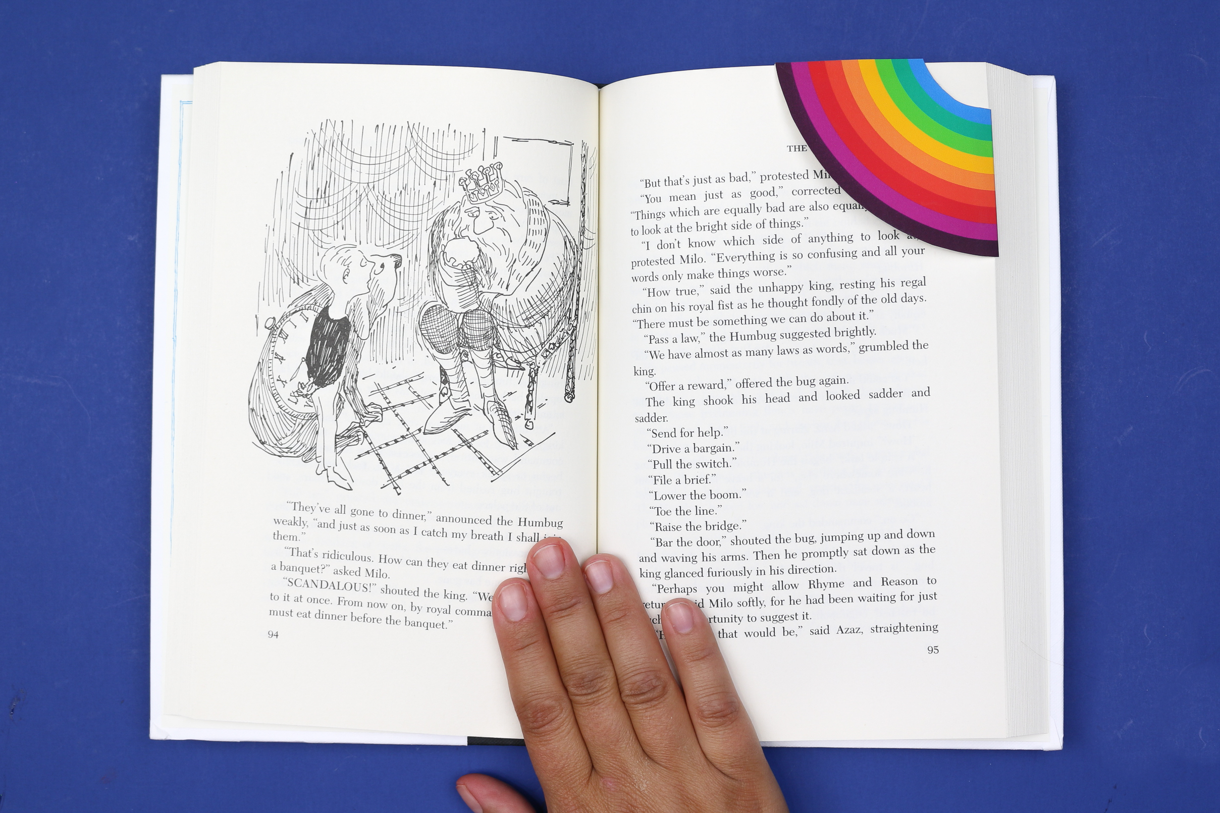 hand holding a book with a rainbow corner bookmark