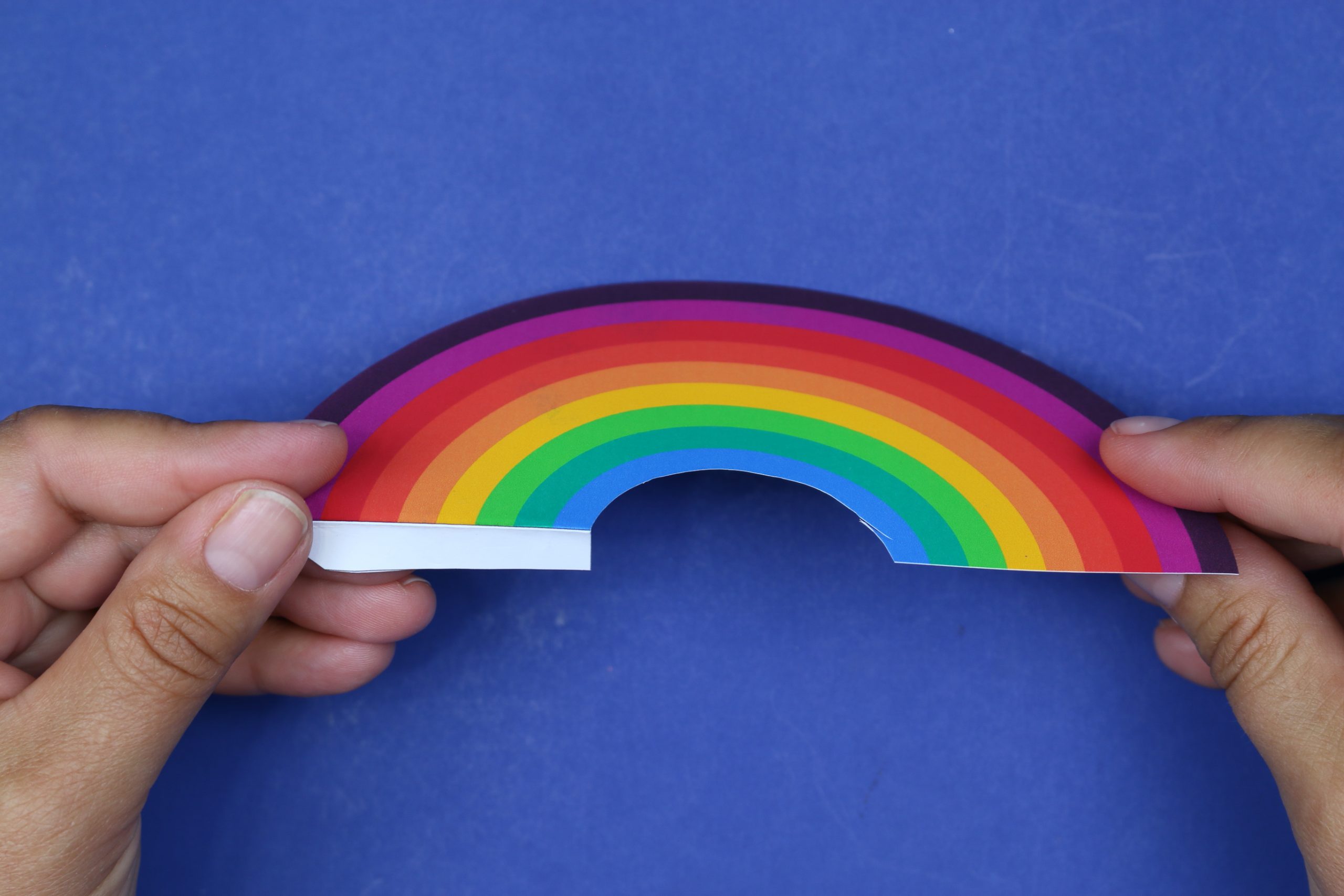 hand holding a rainbow bookmark cut out from paper