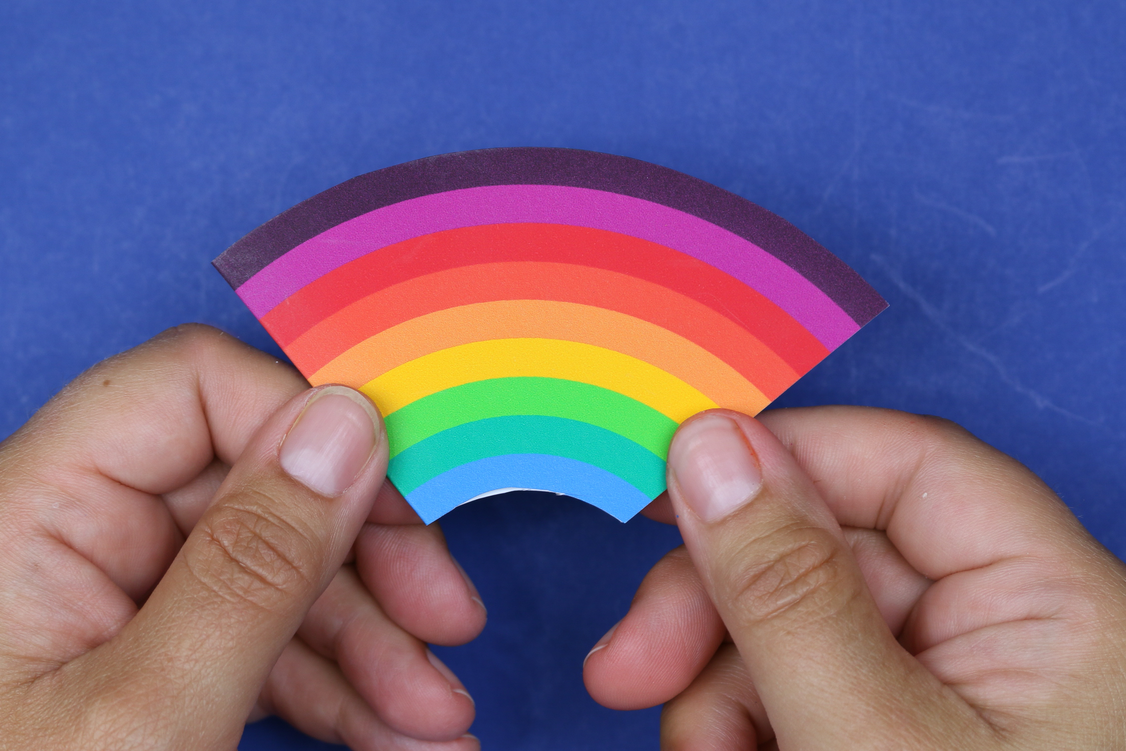 hands holding a rainbow corner bookmark