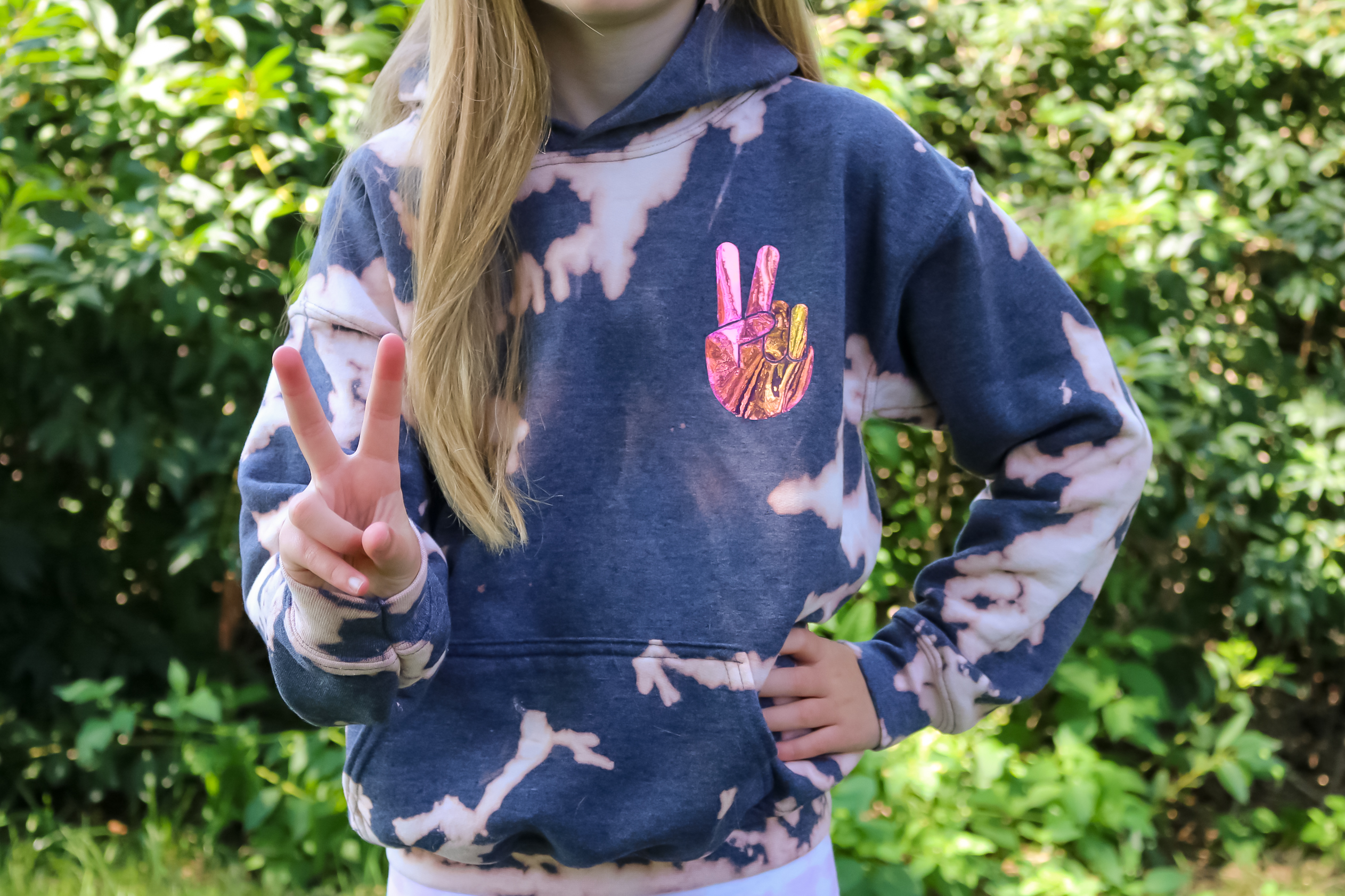 girl wearing bleach dyed sweatshirt and giving the peace sign