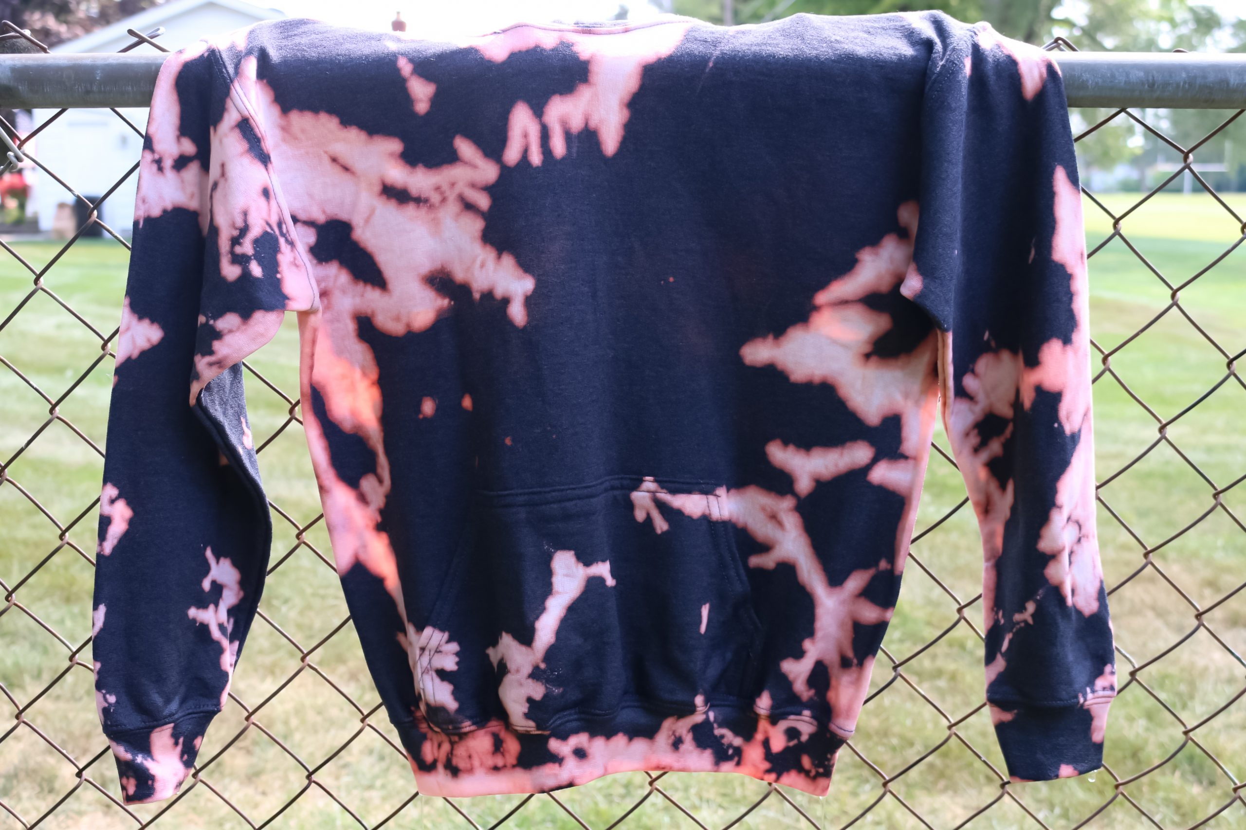 bleach dyed sweatshirt drying on a fence