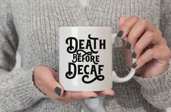 white womans hand holding a mug that reads Death Before Decaf