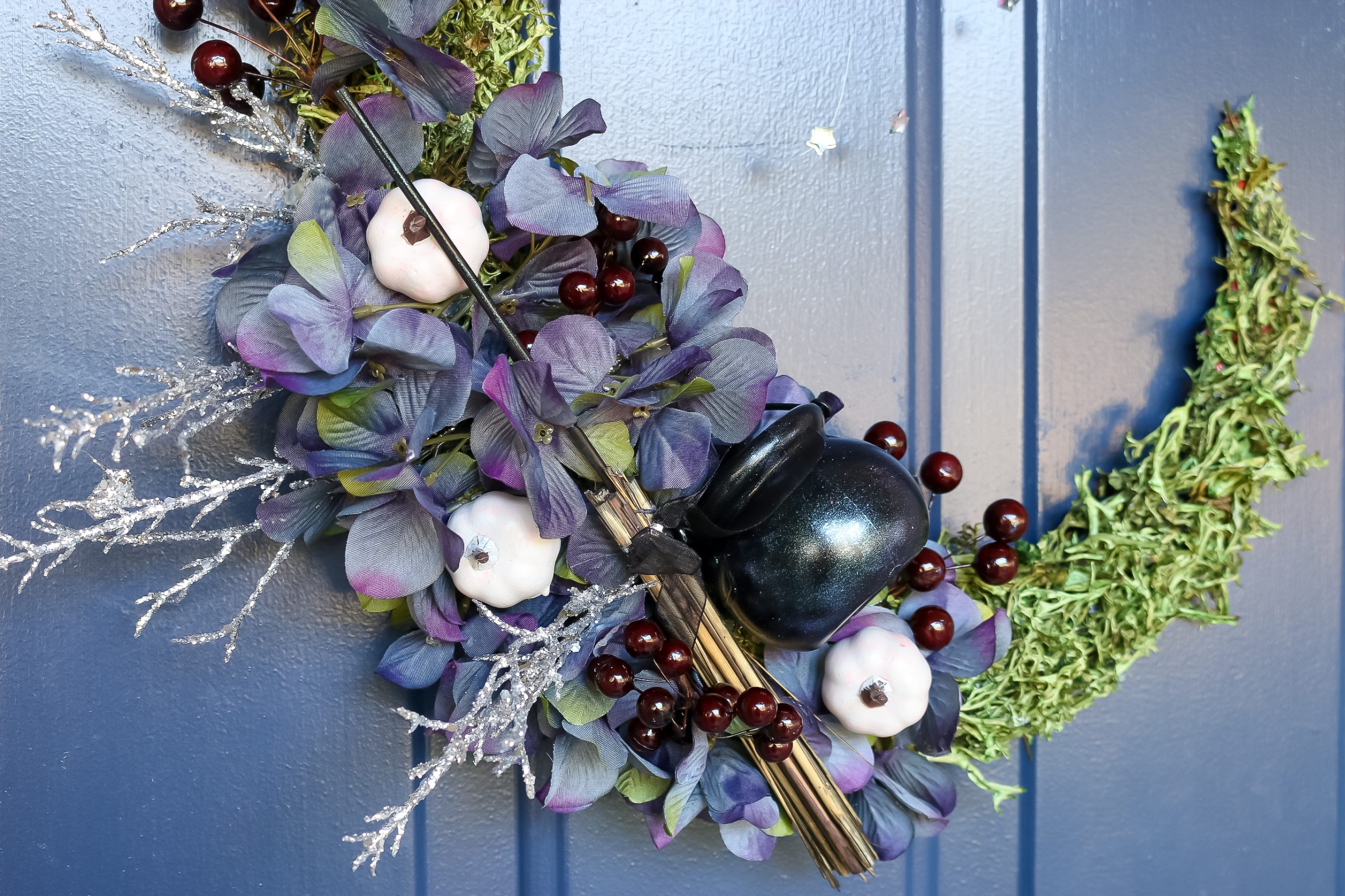 detail of floral crescent moon wreath on a blue door