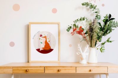 framed fox illustration on a desk near flowers
