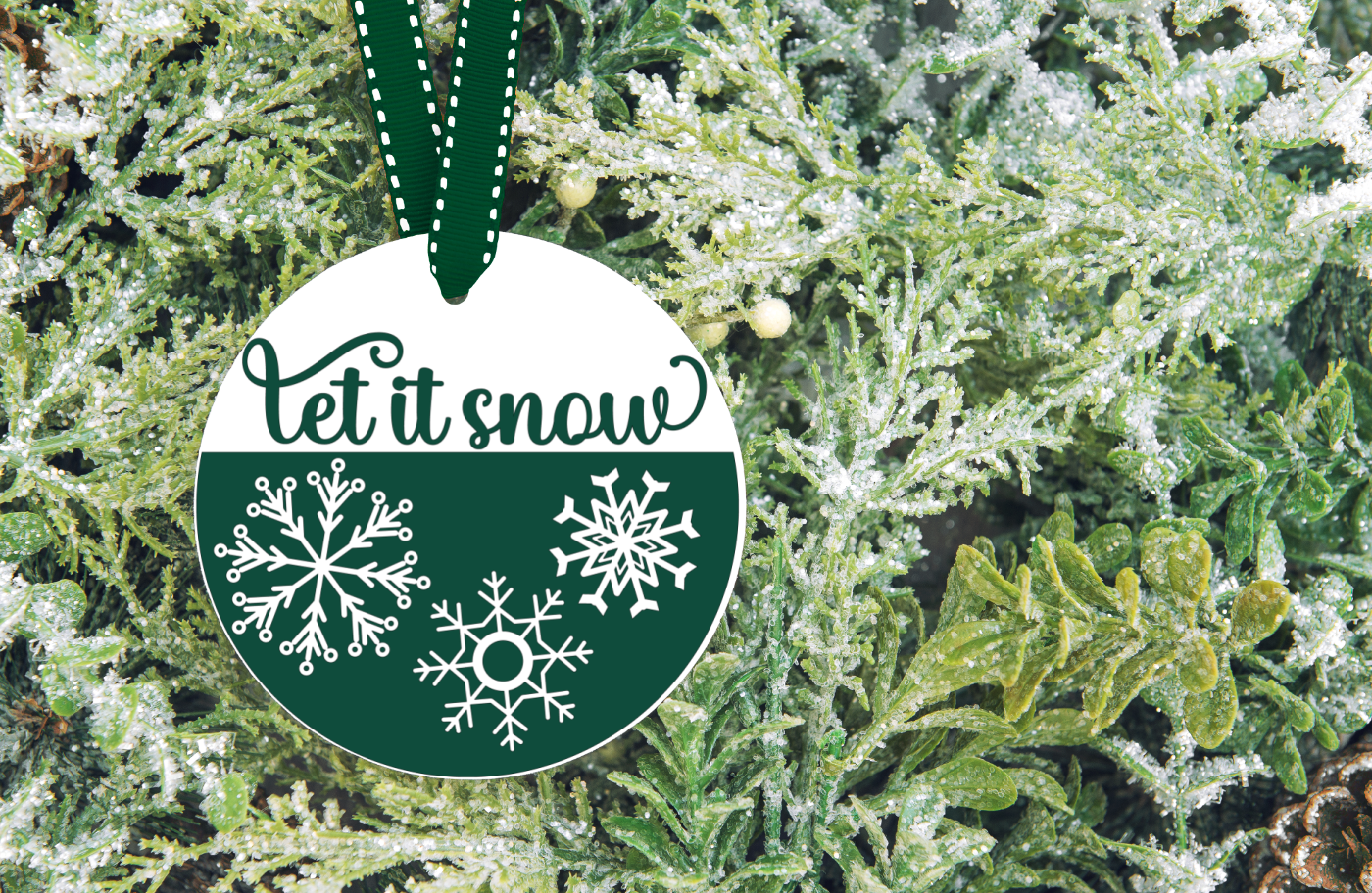 Let It Snow SVG on a flat white ornament hanging on a tree