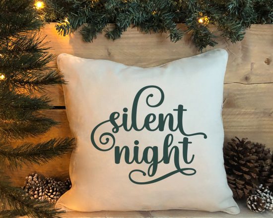 silent night SVG on a pillow near a Christmas tree