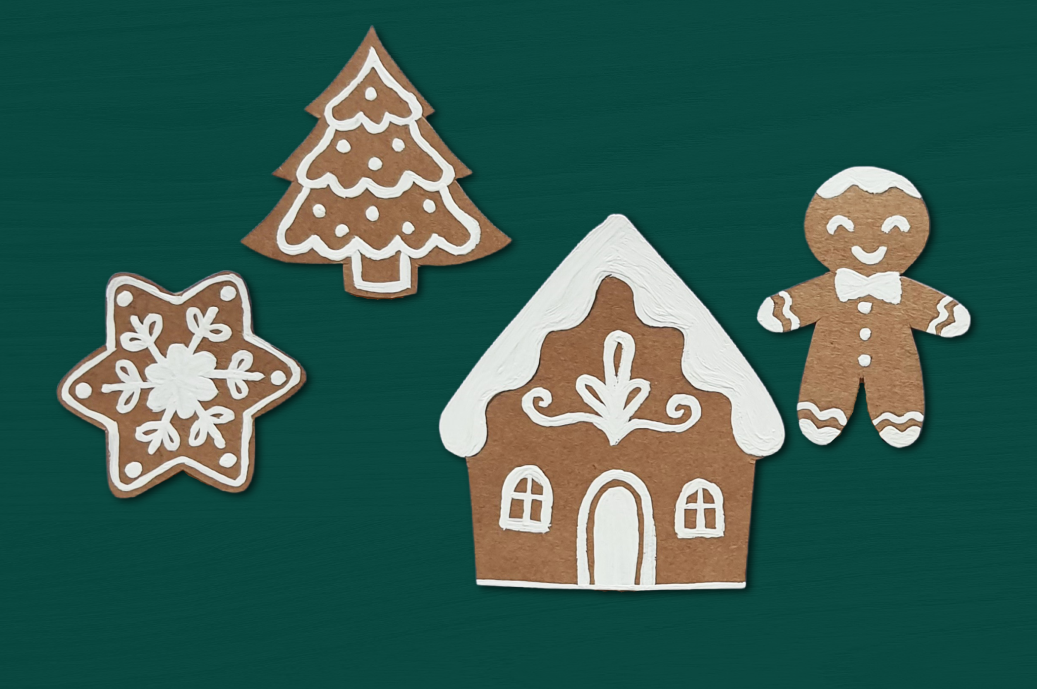 four paper gingerbread cookie ornaments on a green background