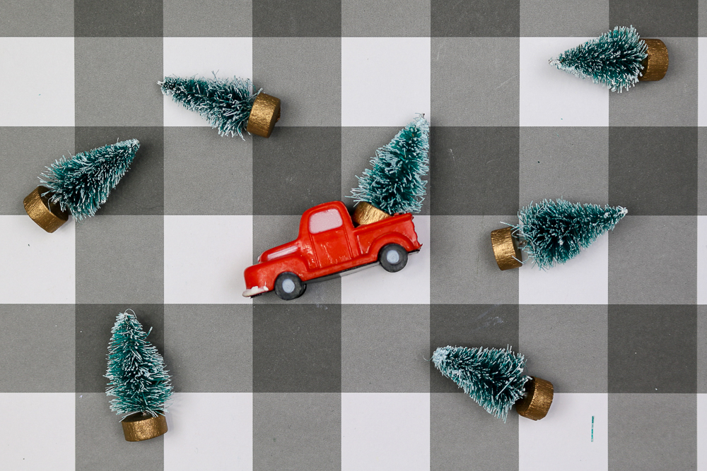 bottle brush trees and red truck figurine on a buffalo check background
