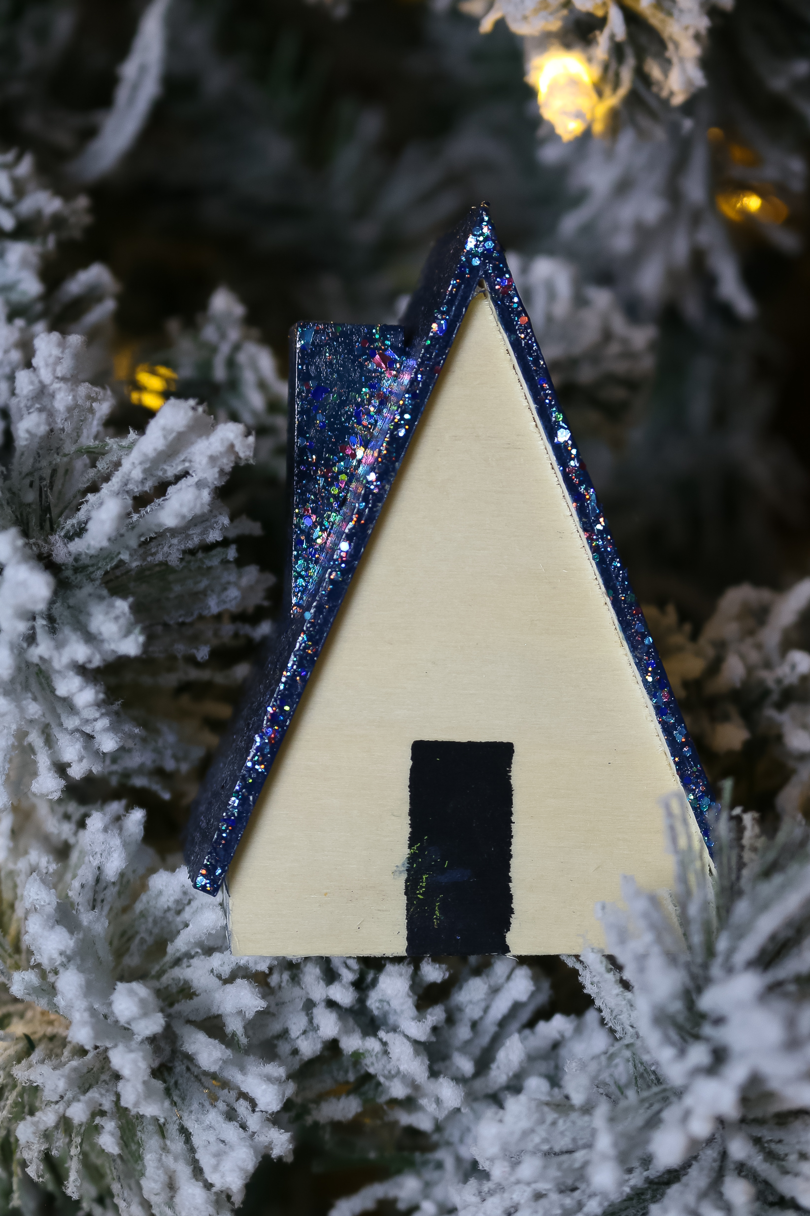 wood house with blue glittered roof in a flocked Christmas tree