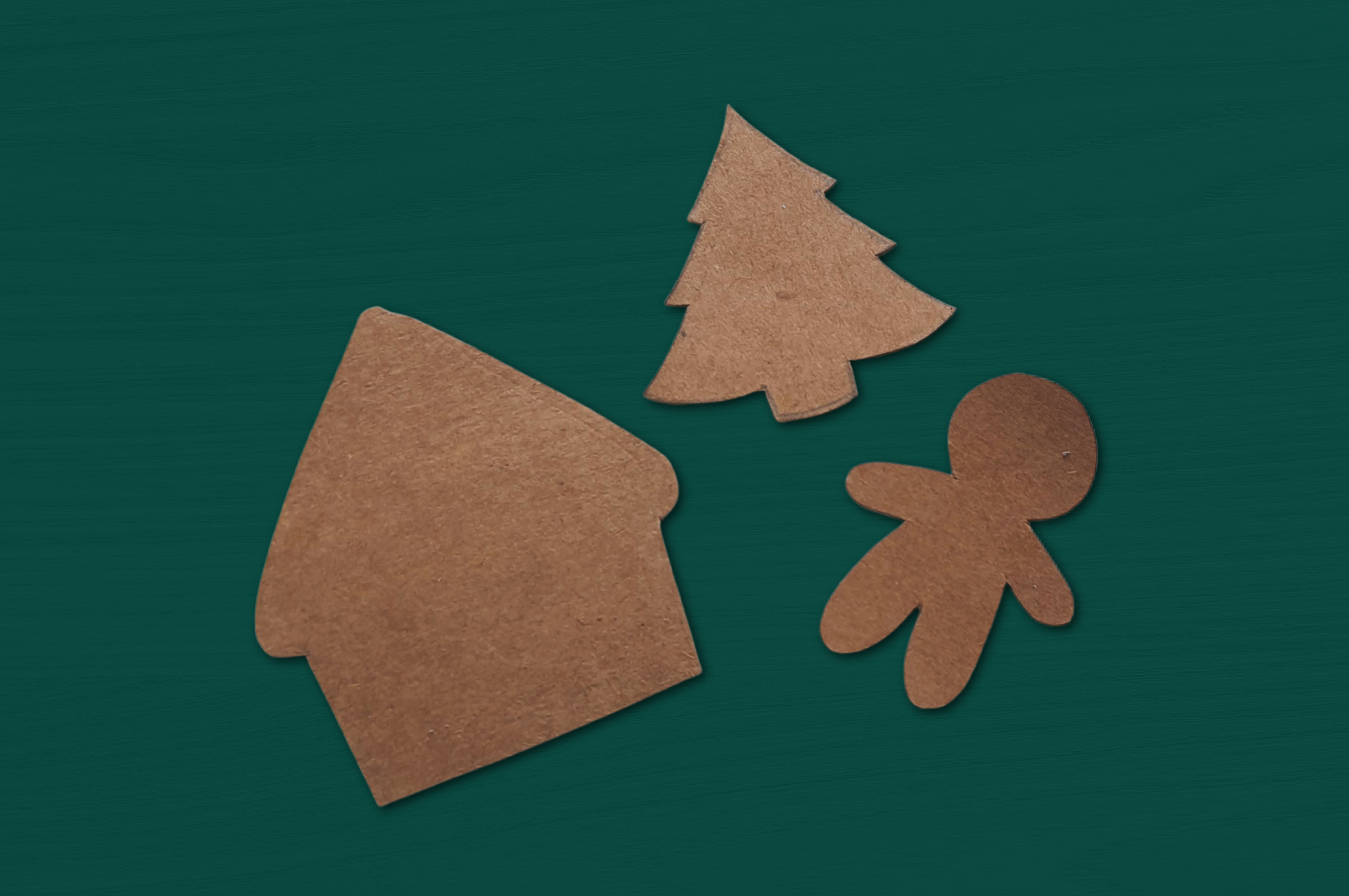 undecorated paper gingerbread ornaments on a green background