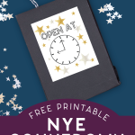 black gift bag with NYE countdown label on a blue background surrounded by star confetti