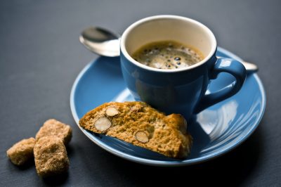biscotti resting on the saucer of a blue coffee cup