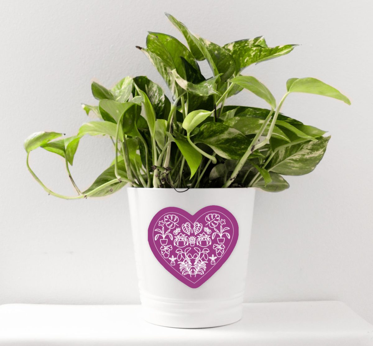 Purple plant heart sticker on a white pot holding a houseplant.