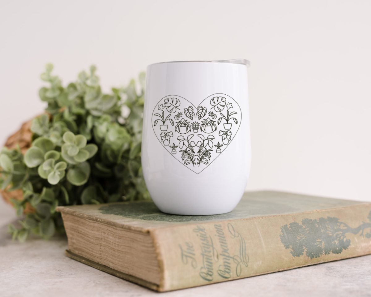 Plant heart SVG design on a wine tumbler near a book and a plant.
