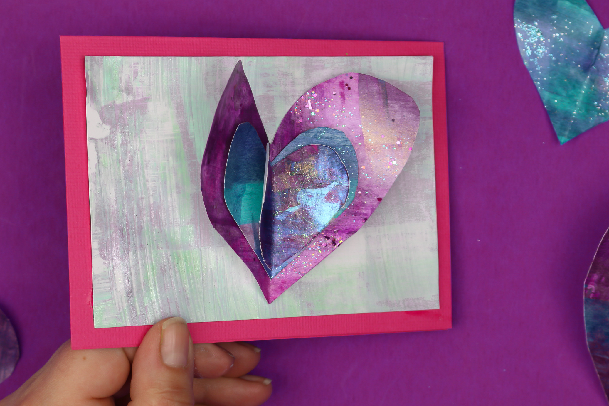 hand holding a diy valentine card with paper heart embellishment
