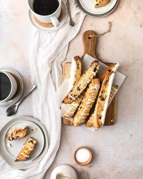 flat lay of cranberry biscotti, mugs of coffee, and baking ingredients