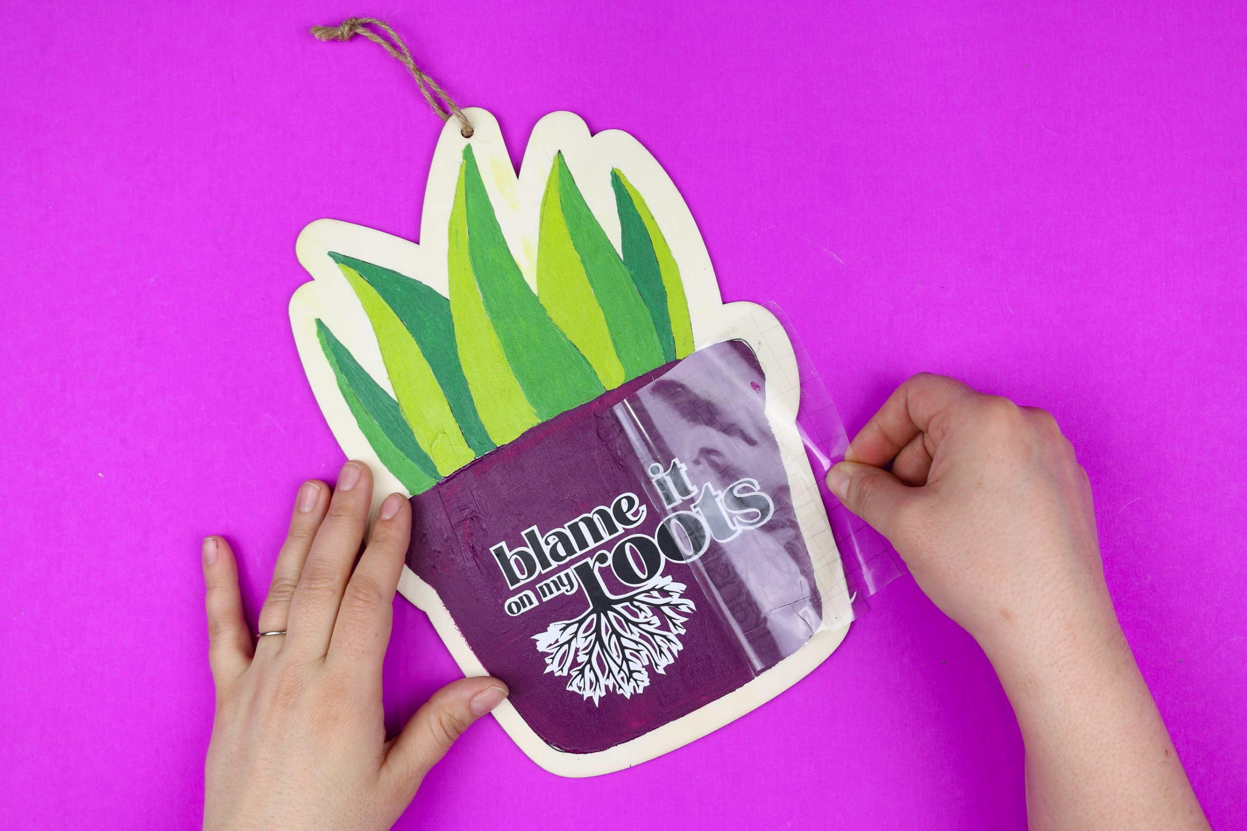 hands removing transfer tape from a painted plant sign