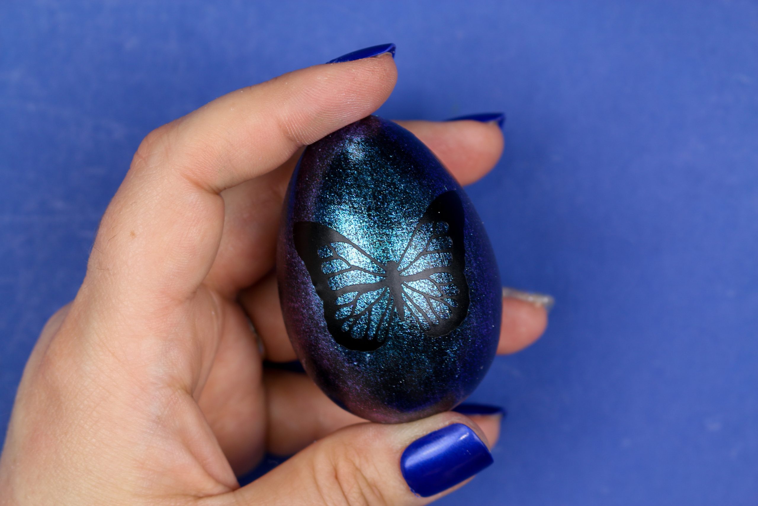woman's hand holding a blue butterfly easter egg