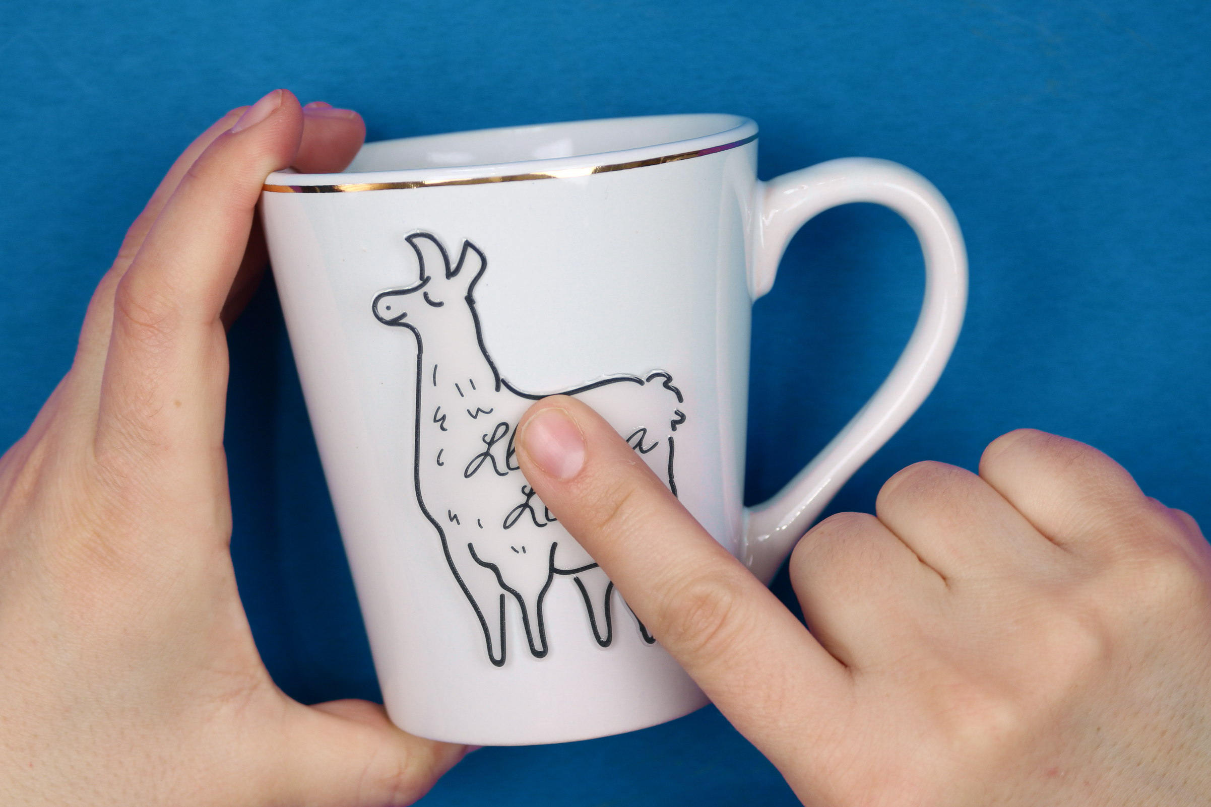 hand applying dollar store ceramic sticker to a mug