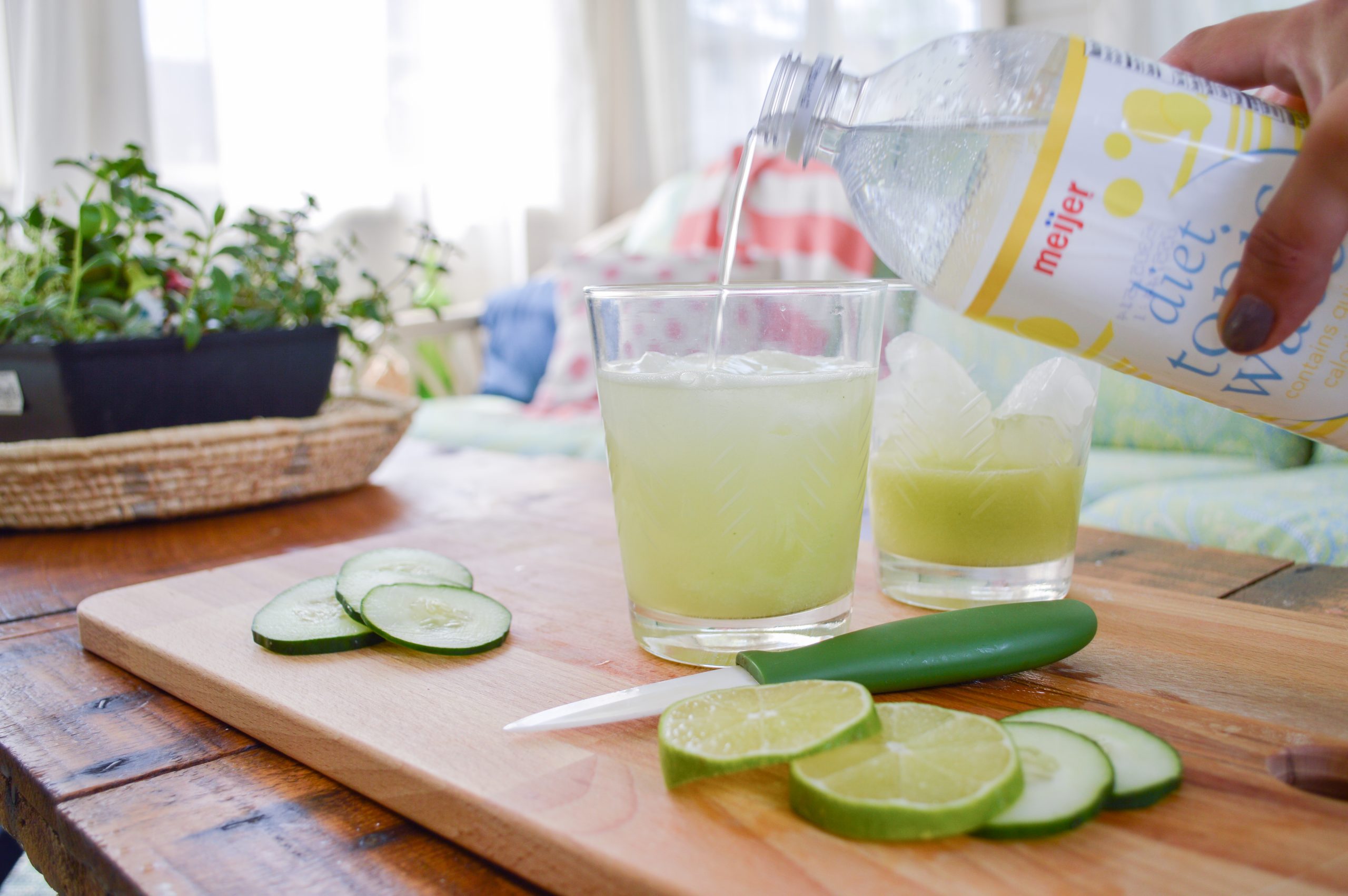 pouring tonic into a cucumber lime gin and tonic