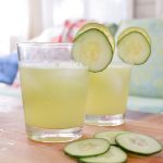 two cucumber lime gin and tonics near sliced cucumbers