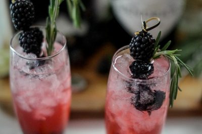 close up of blackberry gin and tonics garnished with fresh berries and rosemary