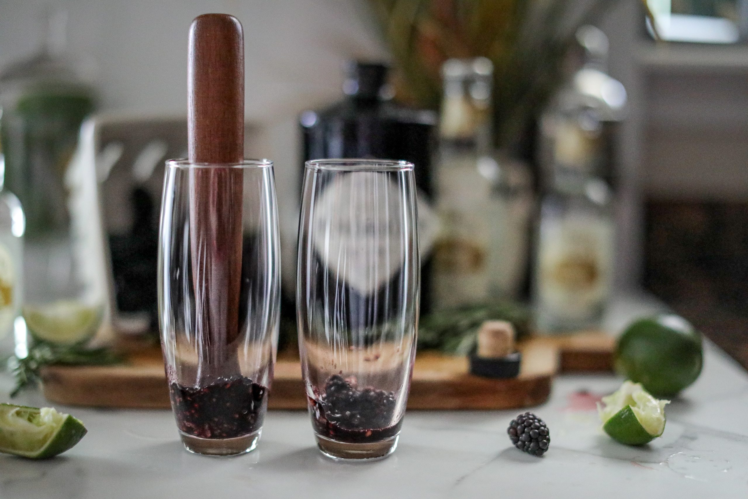 wooden muddler in a cocktail glass with blackberries