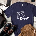 Prost SVG design in vinyl on a blue men's t-shirt surrounded by men's accessories