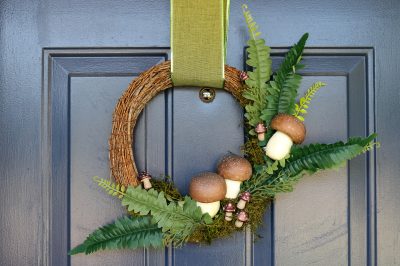front view of a mushroom wreath hanging on a blue door