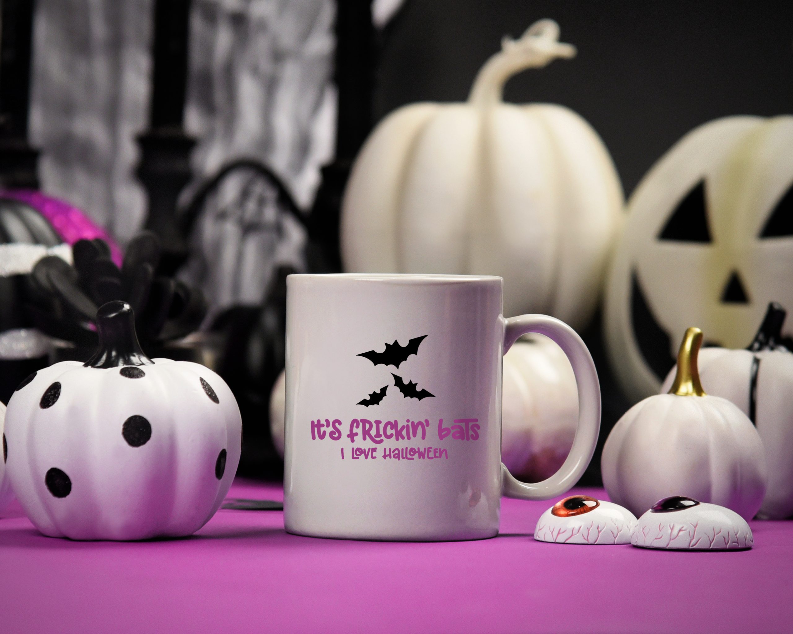 It's Frickin Bats SVG design on a white mug near Halloween decor
