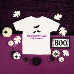 It's Frickin Bats SVG design on a t-shirt near Halloween decor on a purple background