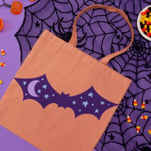 orange tote bag with purple bat design near halloween decor