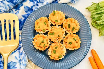 close up of blue plate of buffalo chicken cups near vegetables