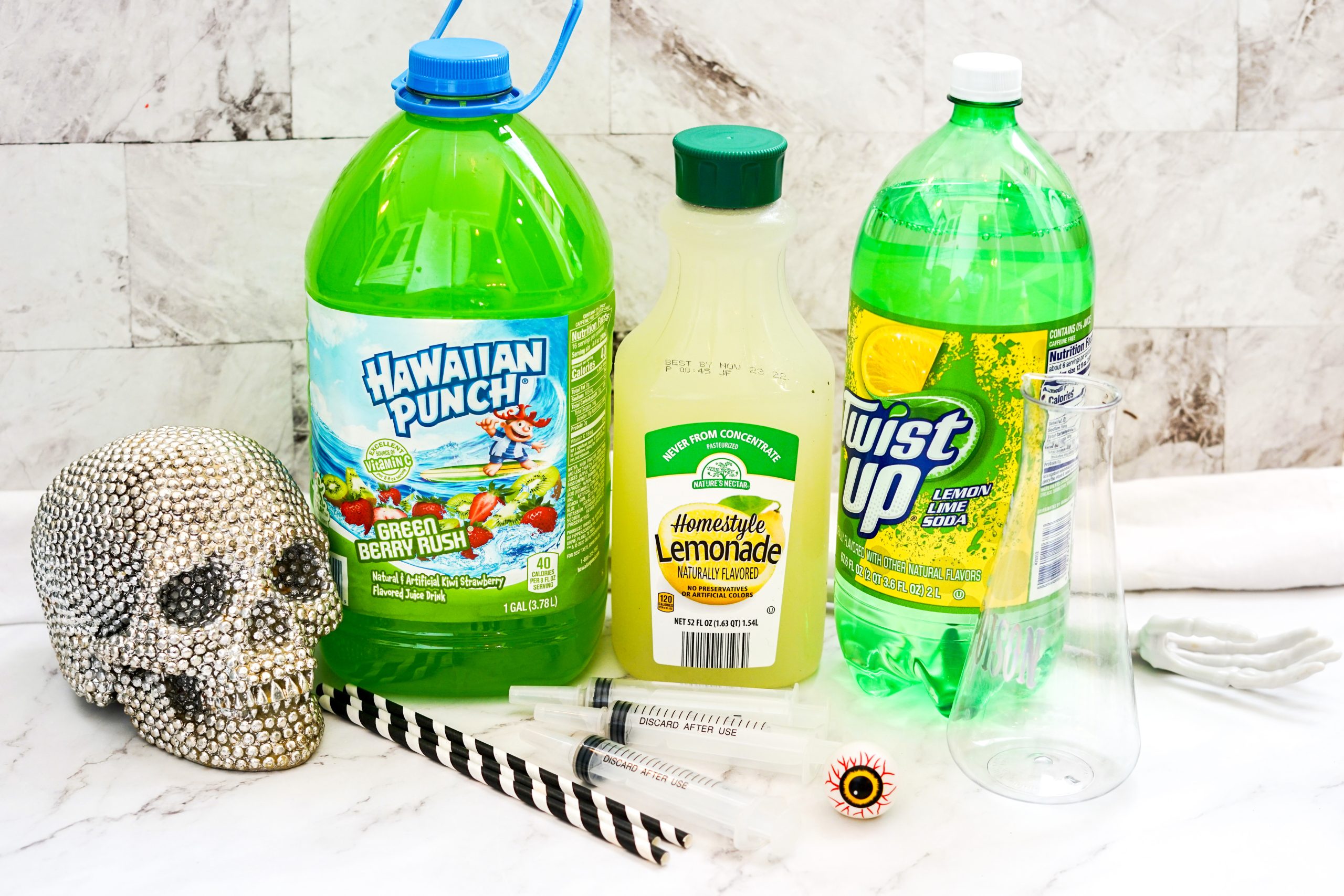 Green Hawaiian punch, lemonade, lemon lime soft drink, and straws on a counter