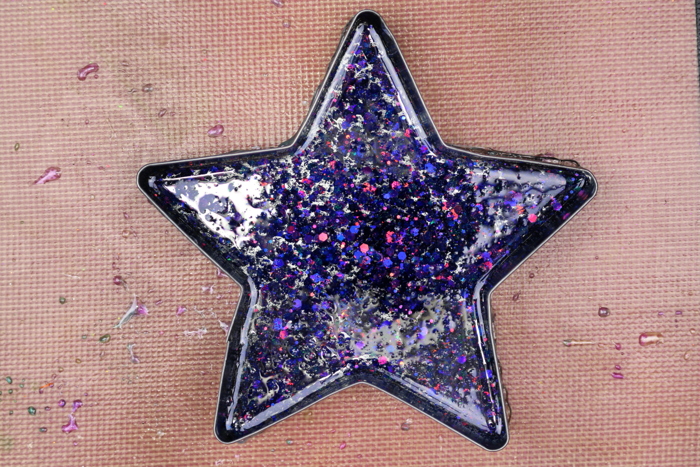 metal tray filled with glitter resin on a silicone mat