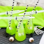 dollar store "poison" beakers filled with green halloween punch near halloween decor