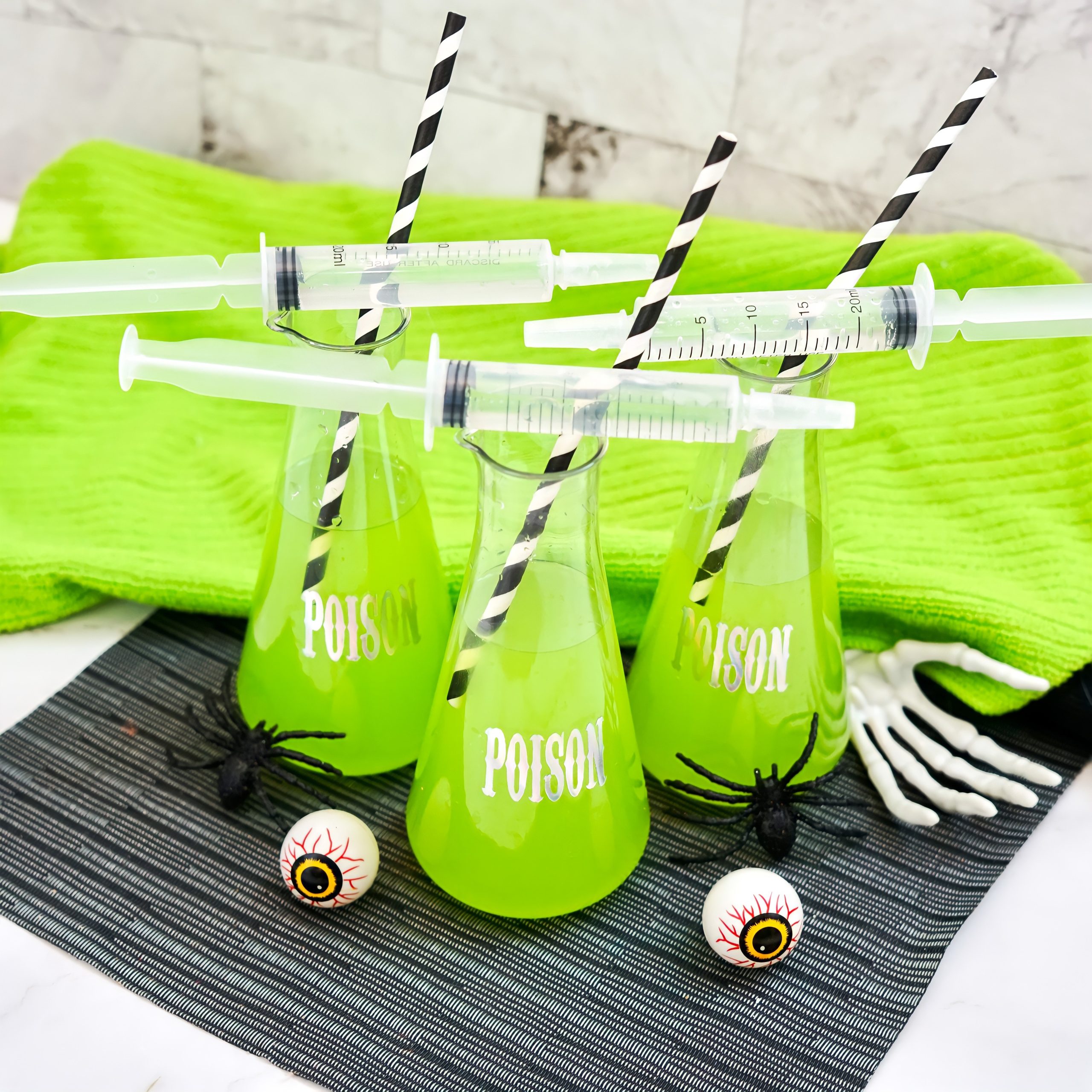 dollar store "poison" beakers filled with green halloween punch near halloween decor