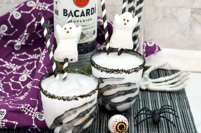 black sugar rimmed cocktail glasses filled with white cocktail and garnished with a Peeps candy ghost near Halloween decor