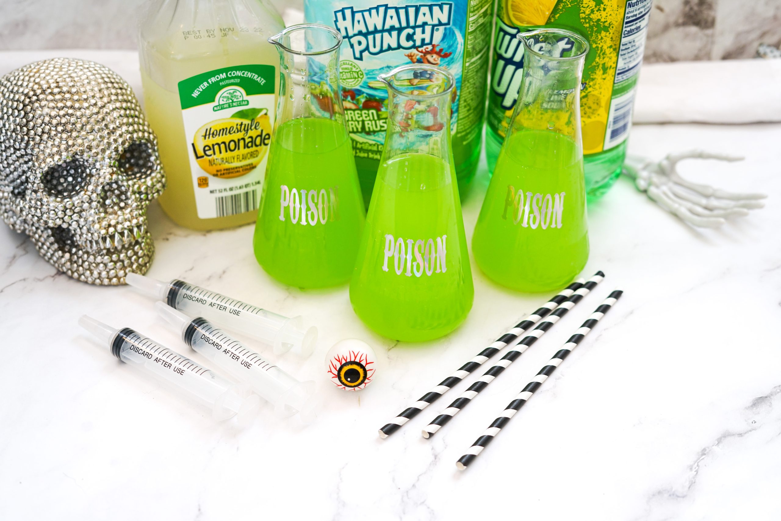 dollar store "poison" beakers filled with green halloween punch near plastic novelty syringes