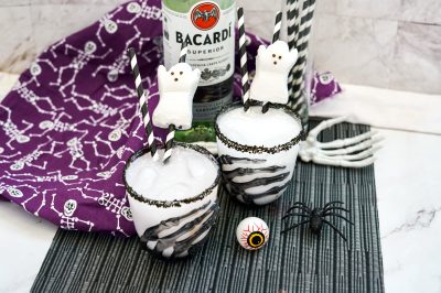 black sugar rimmed cocktail glasses filled with white cocktail and garnished with a Peeps candy ghost