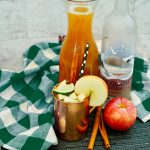 Apple cider mule in a copper mug near the cocktail ingredients