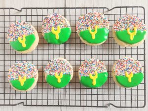 decorated football cookies on a baking rack